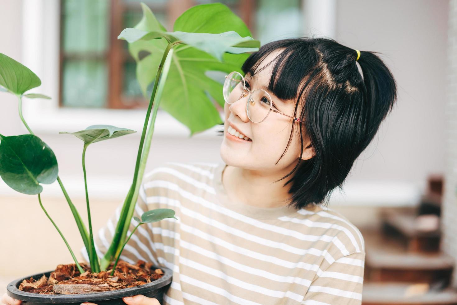 retrato de una joven asiática adulta sosteniendo un árbol de monstera. foto