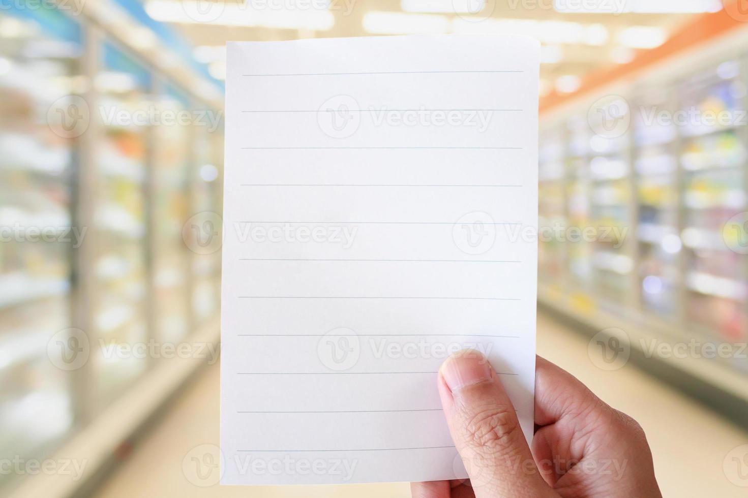 hand hold white paper over supermarket aisle blur background photo
