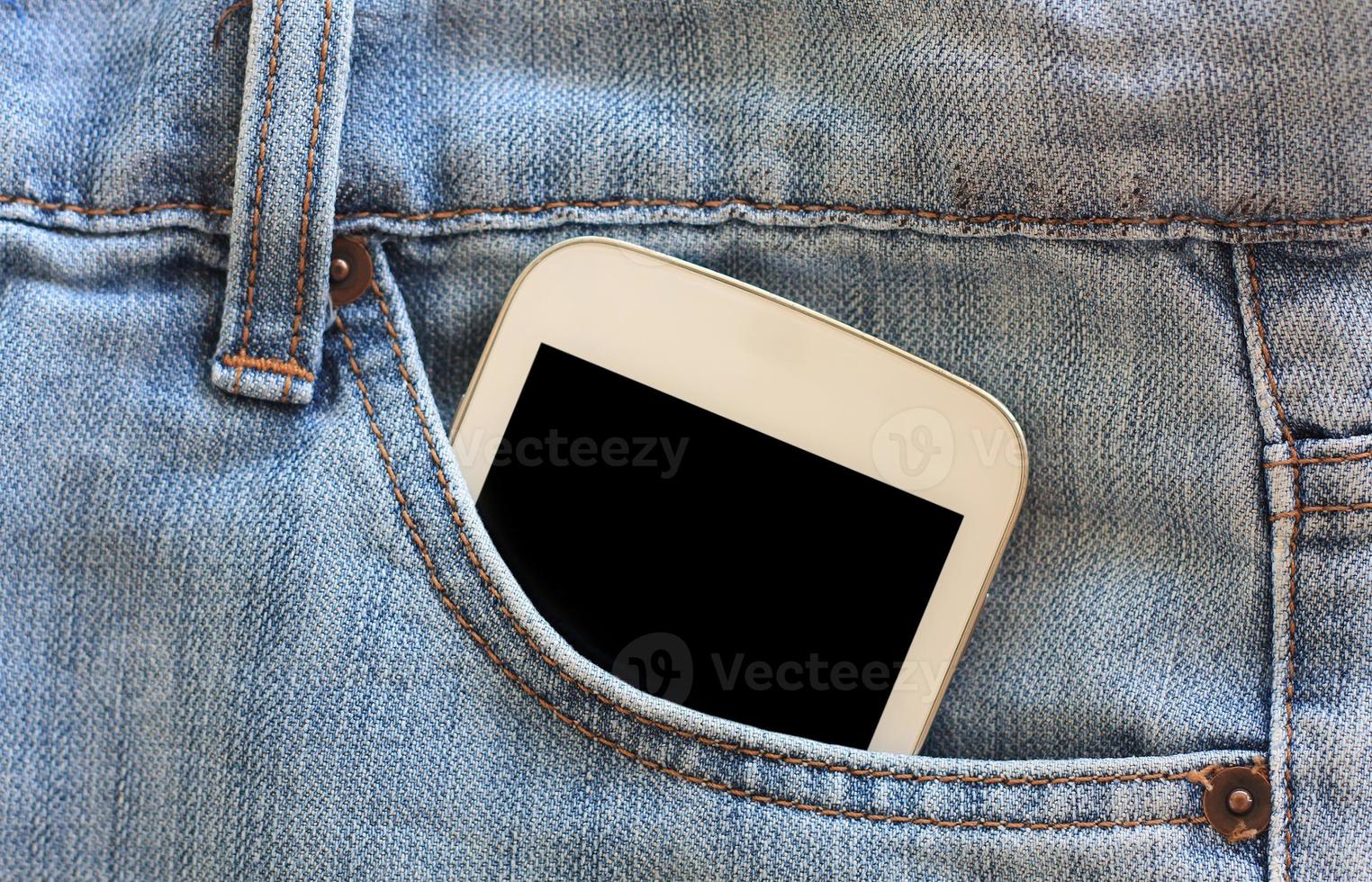 teléfono móvil en el bolsillo de los jeans con pantalla negra foto