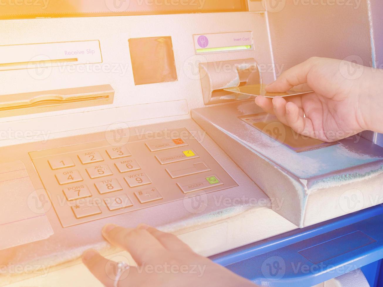 female hand inserting ATM card into ATM bank machine photo