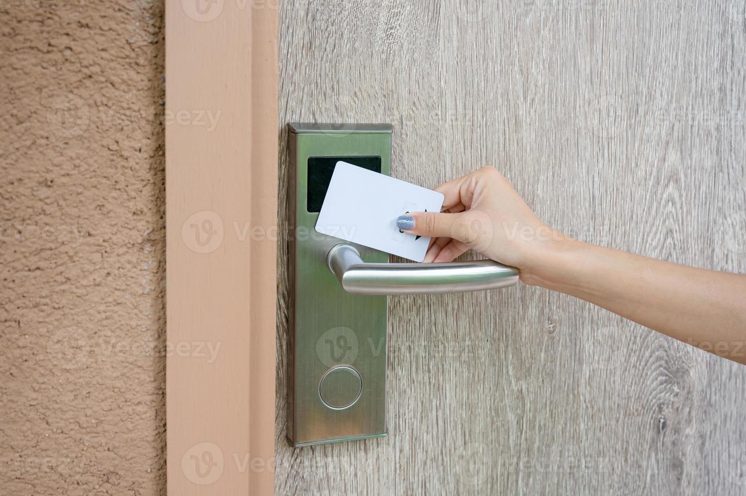 Hand holding key card scanning to unlock wooden door at resort photo