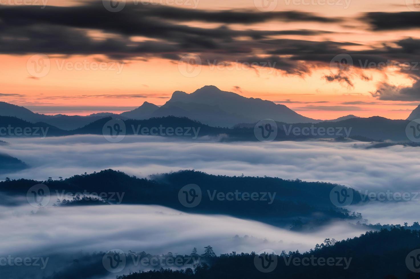 Sunrise over mountain range and sea of fog flowing on hill in national park photo
