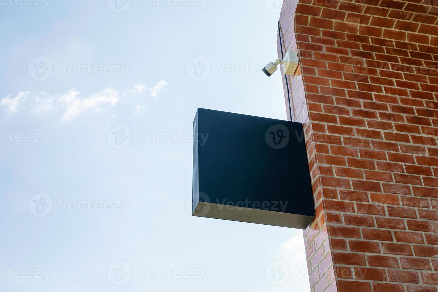 Empty shop signage with CCTV security camera hanging on brick wall photo