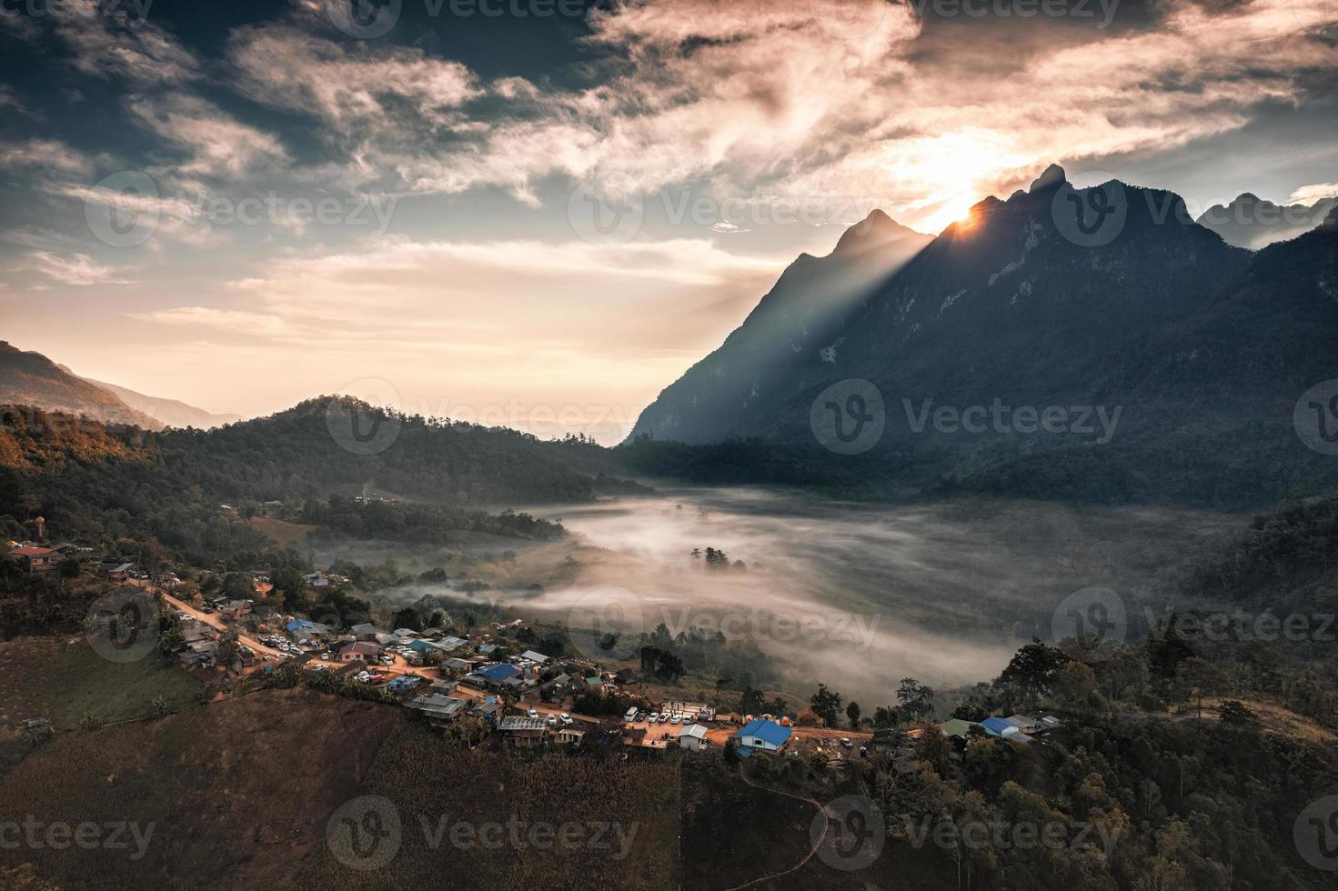 Aerial view of sunrise over mountain range with foggy and local traditional village on hill in tropical rainforest at national park photo