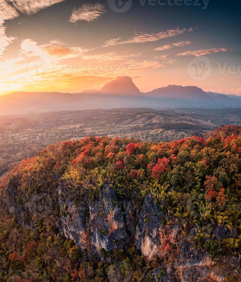 Sunset over mountain range with colorful autumn forest on hill in countryside photo