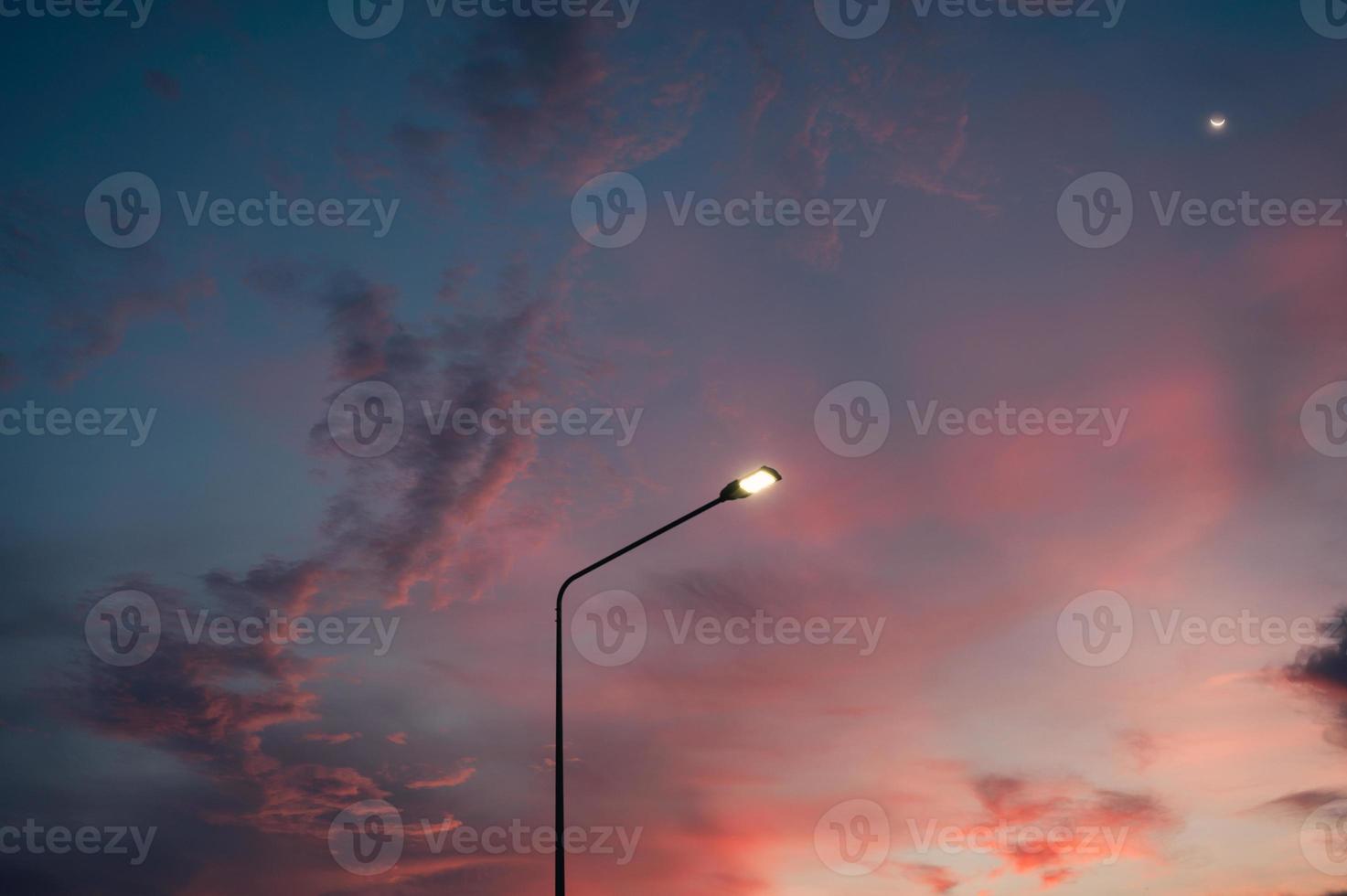Street light pole with the moon and evening sky photo