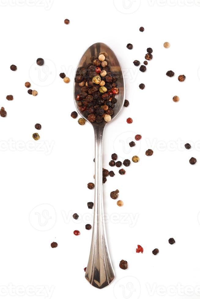 Metallic spoon and dried pepper grains photo