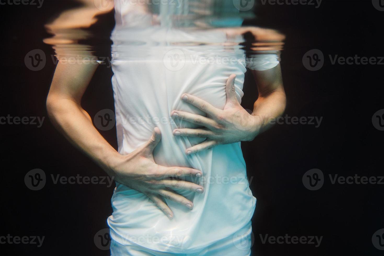 manos bailando bajo el agua sobre fondo negro en la piscina foto