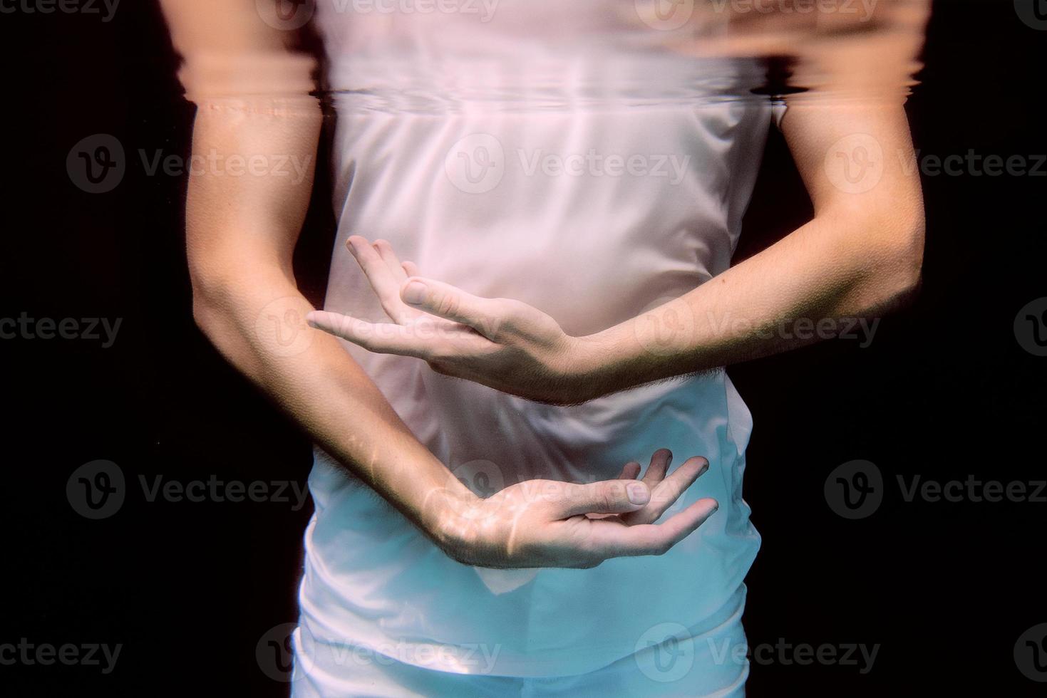 manos bailando bajo el agua sobre fondo negro en la piscina foto