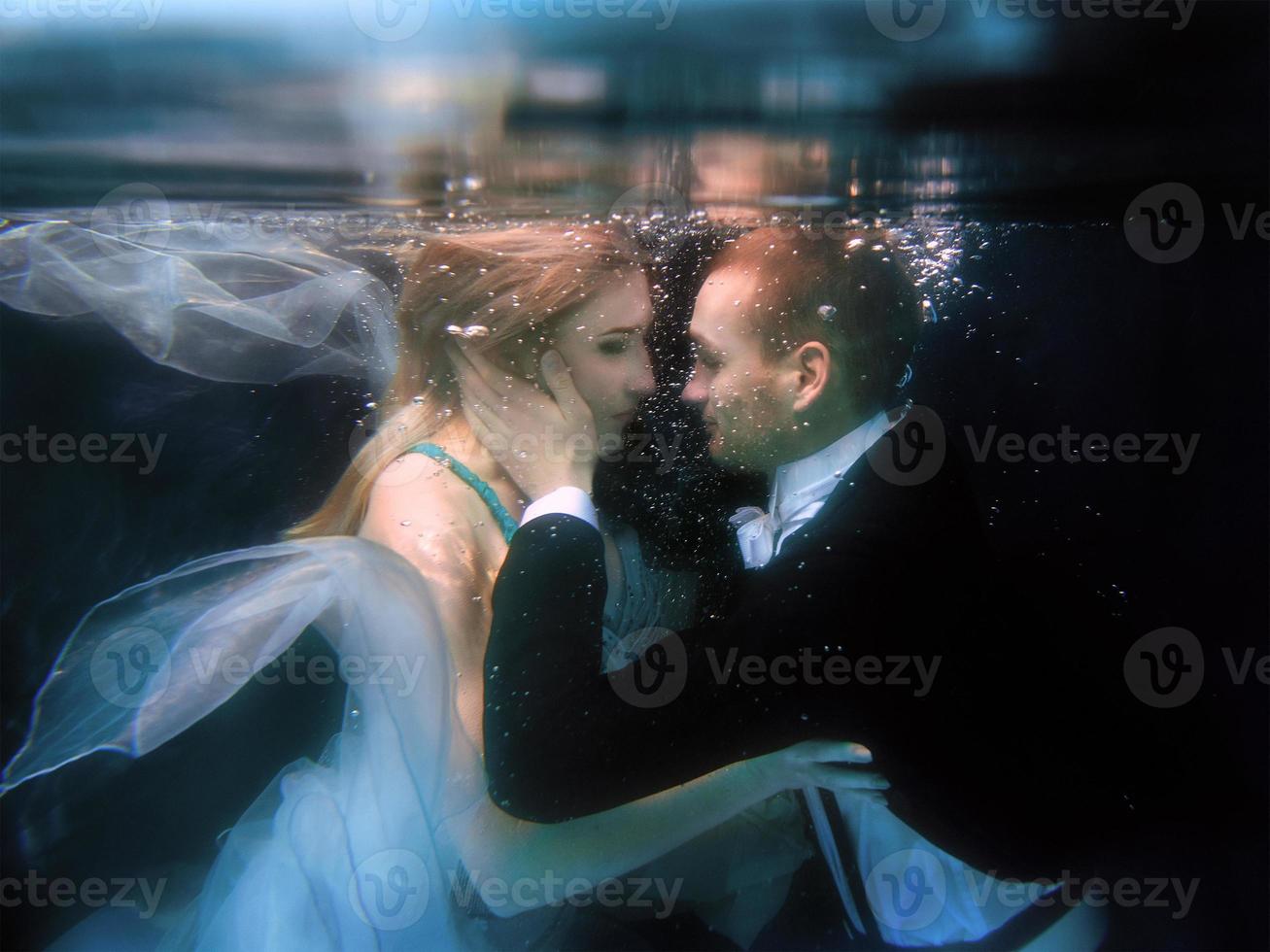 hermosa pareja bailando bajo el agua en la piscina foto