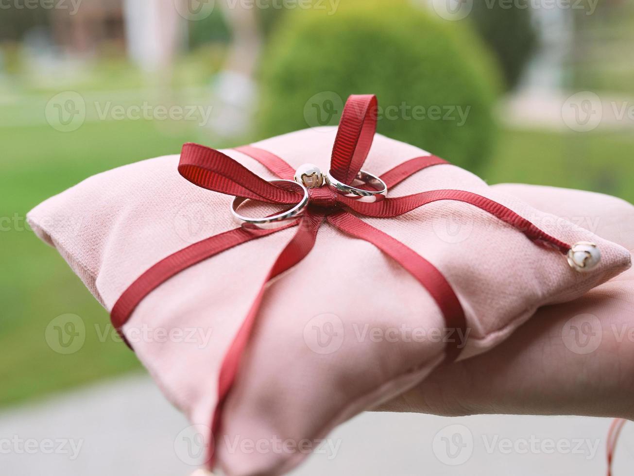 anillos de oro blanco de boda en almohada rosa como símbolos de amor y matrimonio foto