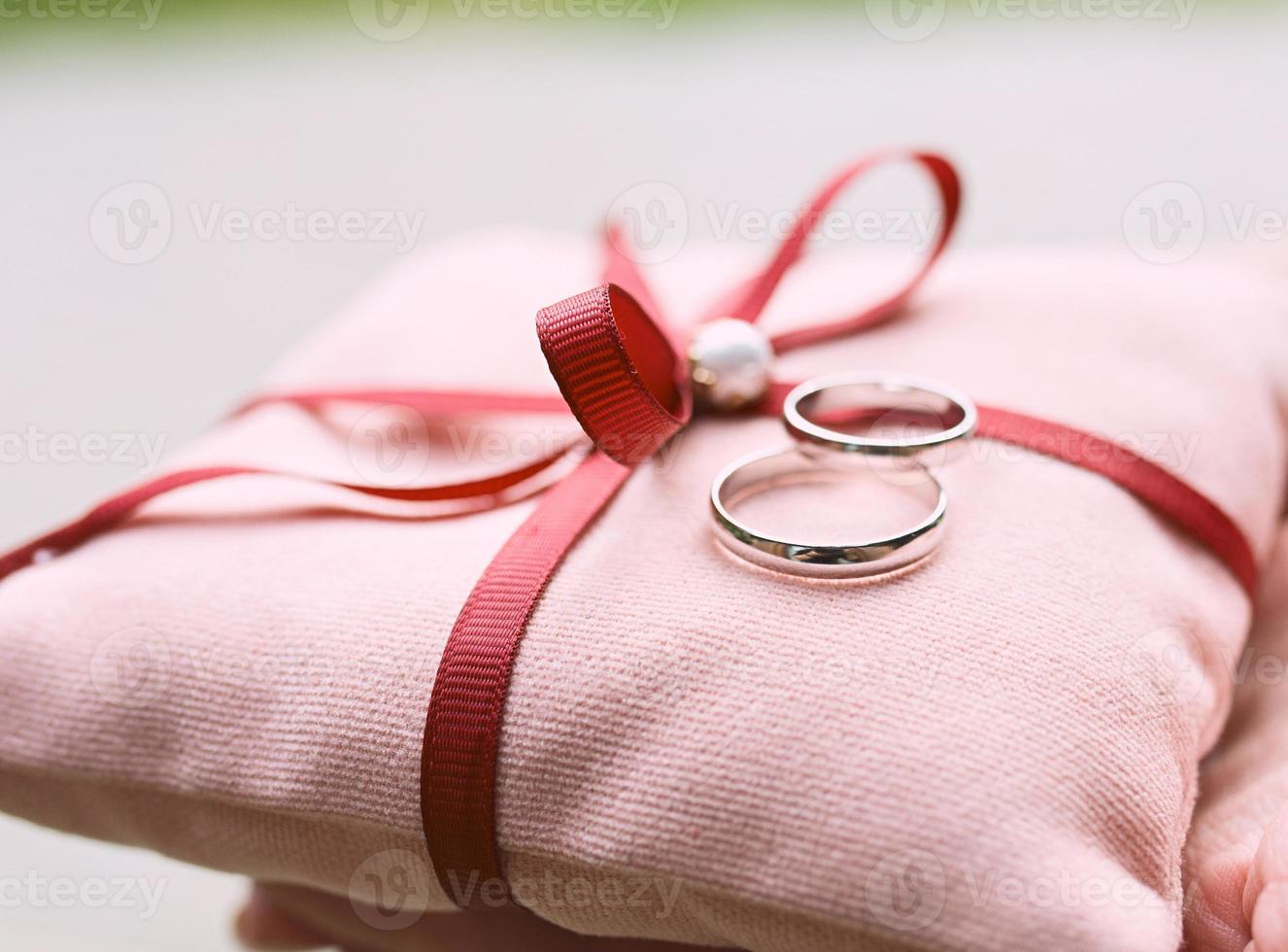 anillos de oro blanco de boda en almohada rosa como símbolos de amor y matrimonio foto