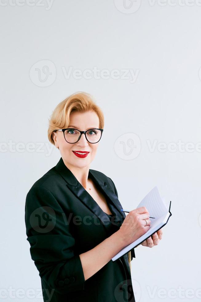 Mature beautiful business woman making plans and notes on white background. Education, business, management concept photo