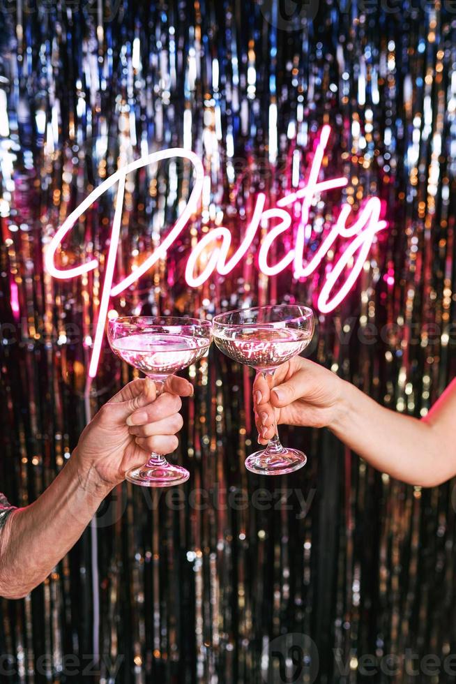 dos manos de mujeres maduras bebiendo vino espumoso en la fiesta. vacaciones, evento de vida, concepto de celebración. foto