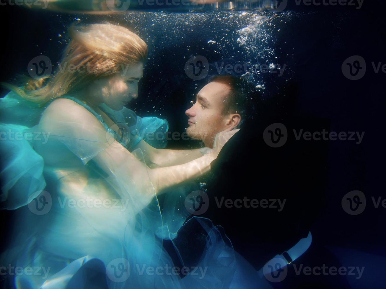 beautiful couple dancing underwater in the swimming pool photo