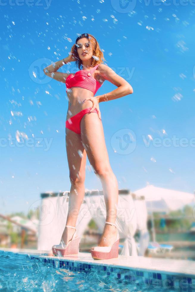 mujer hermosa joven que se divierte en verano en la piscina foto