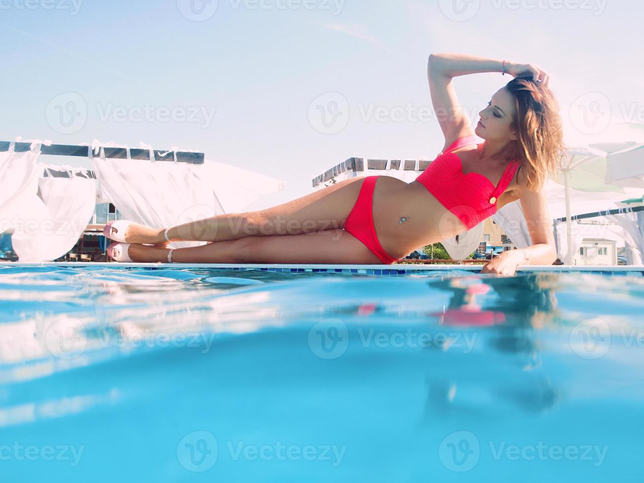 mujer hermosa joven que se divierte en verano en la piscina foto