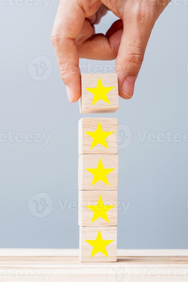 Hand holding wooden blocks with the star symbol. Customer reviews, feedback, rating, ranking and service concept. photo