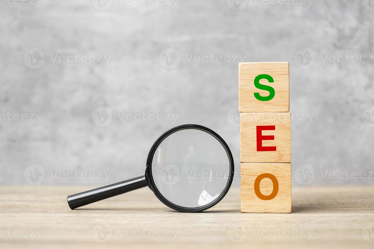 SEO Search Engine Optimization text wooden cube blocks and hand holding magnifying glass on table. Idea, Strategy, advertising, marketing, Keyword and Content concept photo