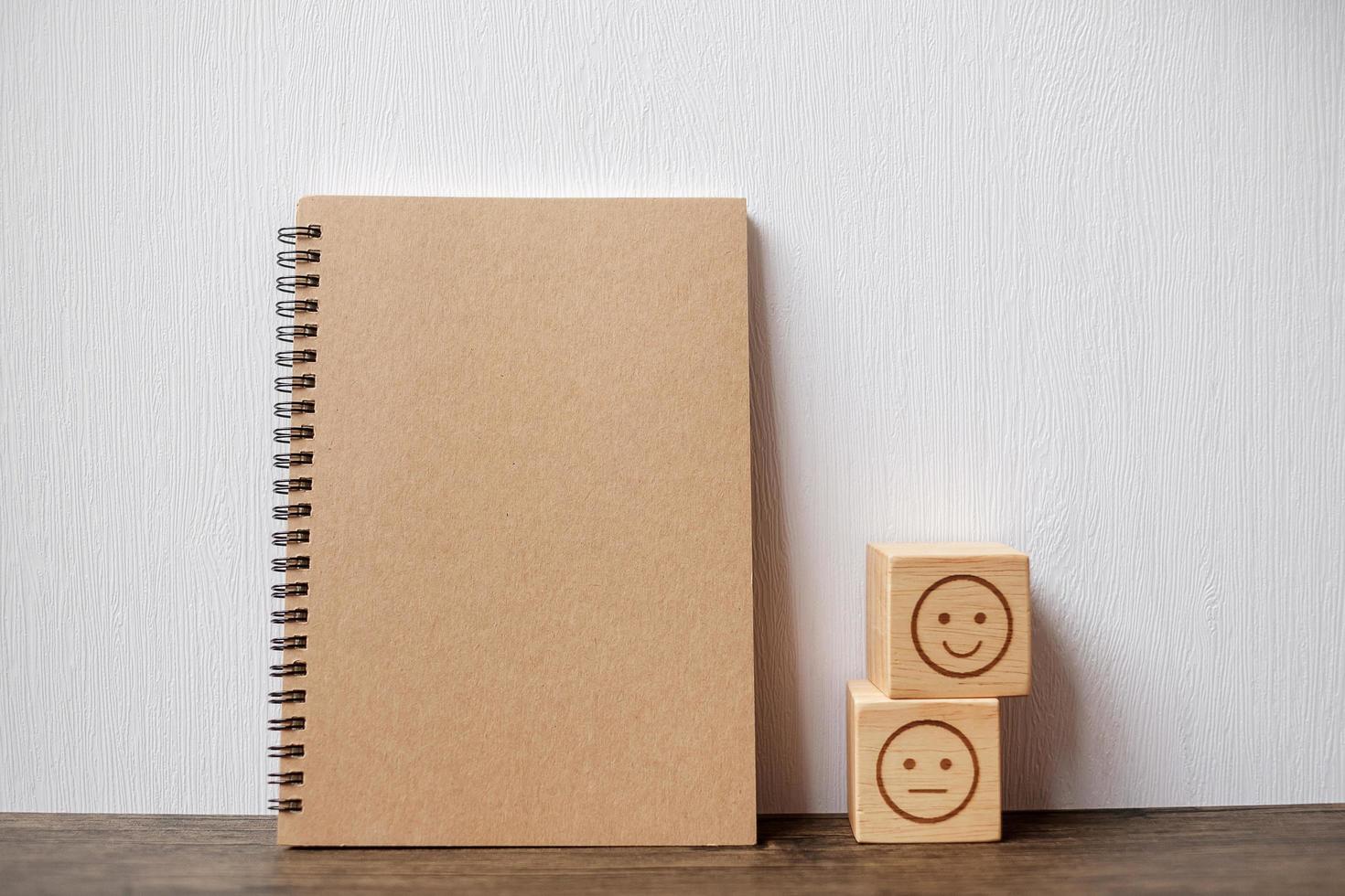 emotion face block and notebook on table. Emoticon for customer review, satisfaction, mood, mental health and feedback concept photo