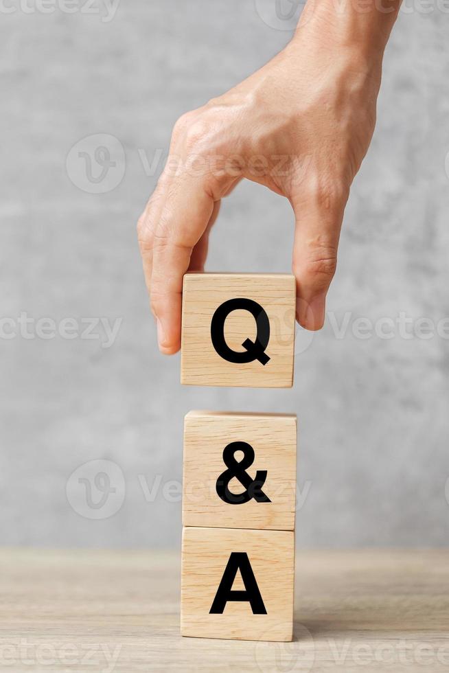 Hand holding Q and A word with wooden block. FAQ frequency asked questions, Answer, Question  Ask, Information, Communication and Brainstorming Concepts photo