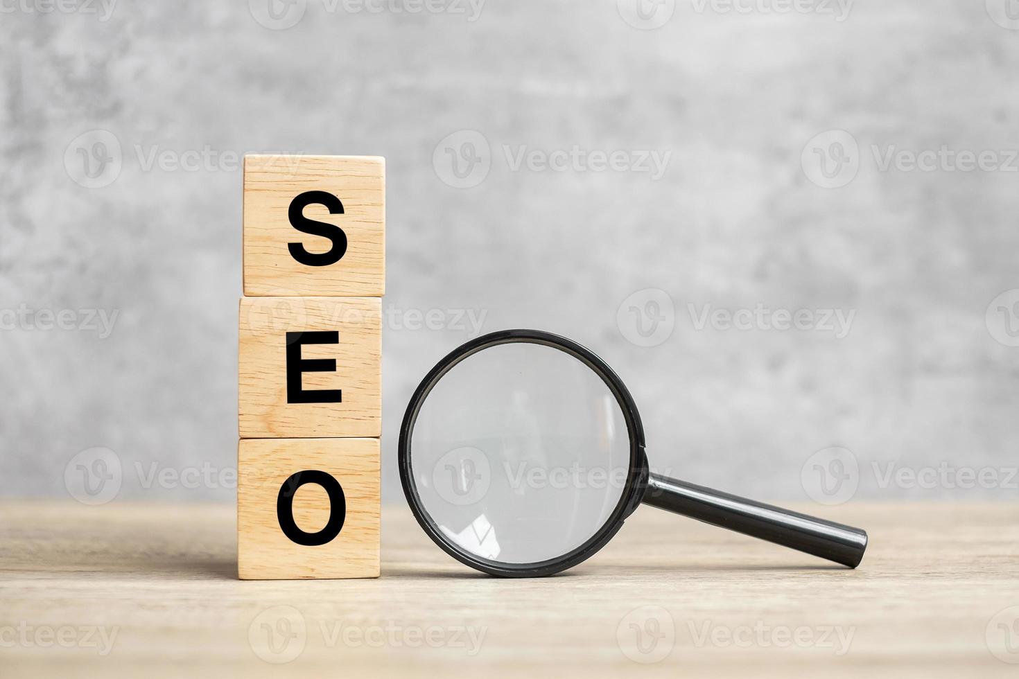 SEO Search Engine Optimization text wooden cube blocks and hand holding magnifying glass on table. Idea, Strategy, advertising, marketing, Keyword and Content concept photo