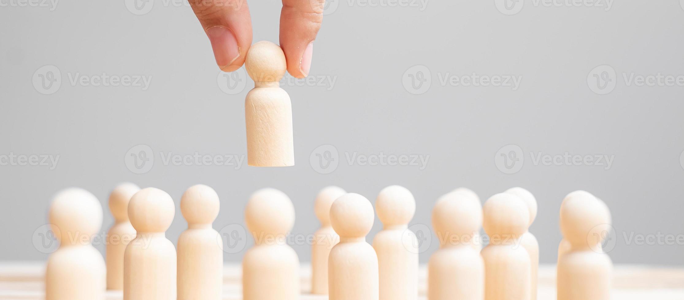 Businessman hand pulling leader man wooden from crowd of employees. Toxic People, Human resource management, Recruitment, Teamwork and leadership Concepts photo