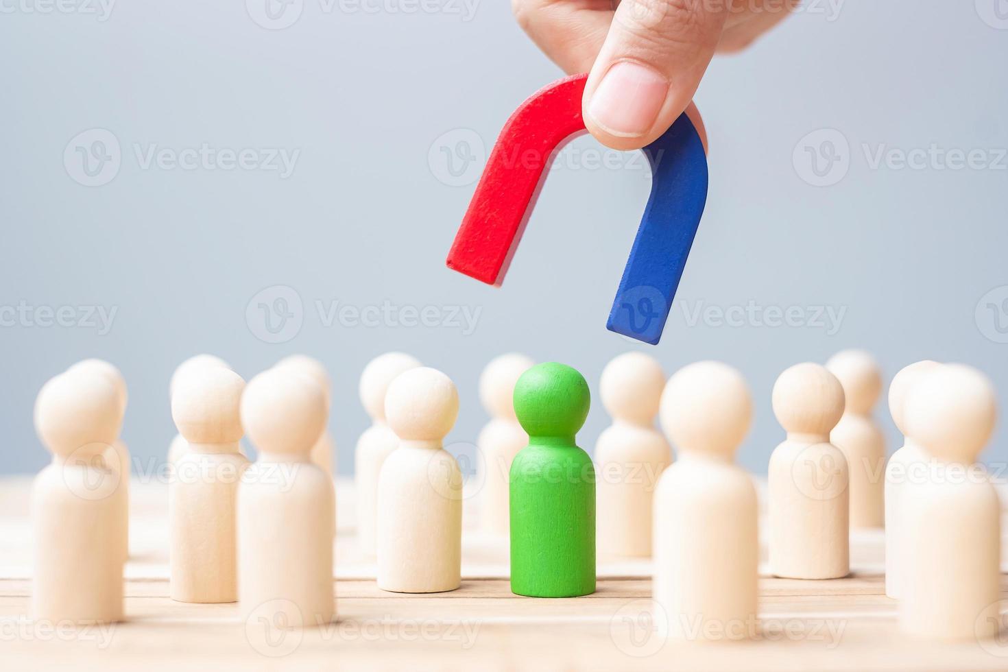 Business man hand holding magnet and pulling man wooden figure from the crowd employee. Business, Human resource management, Recruitment, Teamwork, strategy, toxic people and leadership Concepts photo