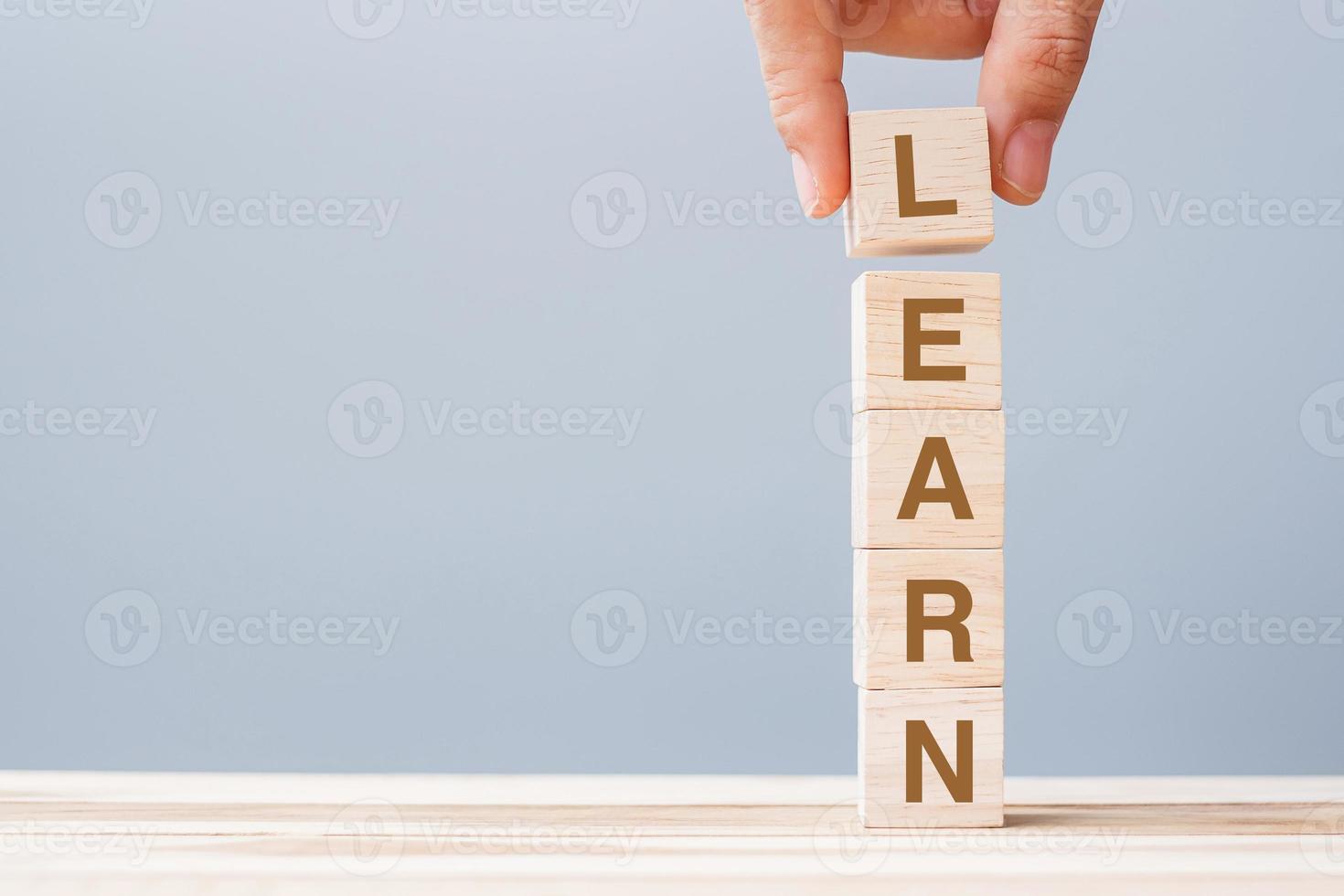 mano de hombre de negocios sosteniendo bloque de cubo de madera con aprender palabra de negocios en el fondo de la mesa. aprendizaje, educación conocimiento, estudio y sabiduría foto