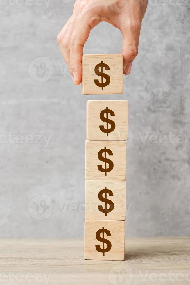 Businessman hand holding wooden blocks with the American Dollar symbol. Money, cash, currency and investment concept. photo