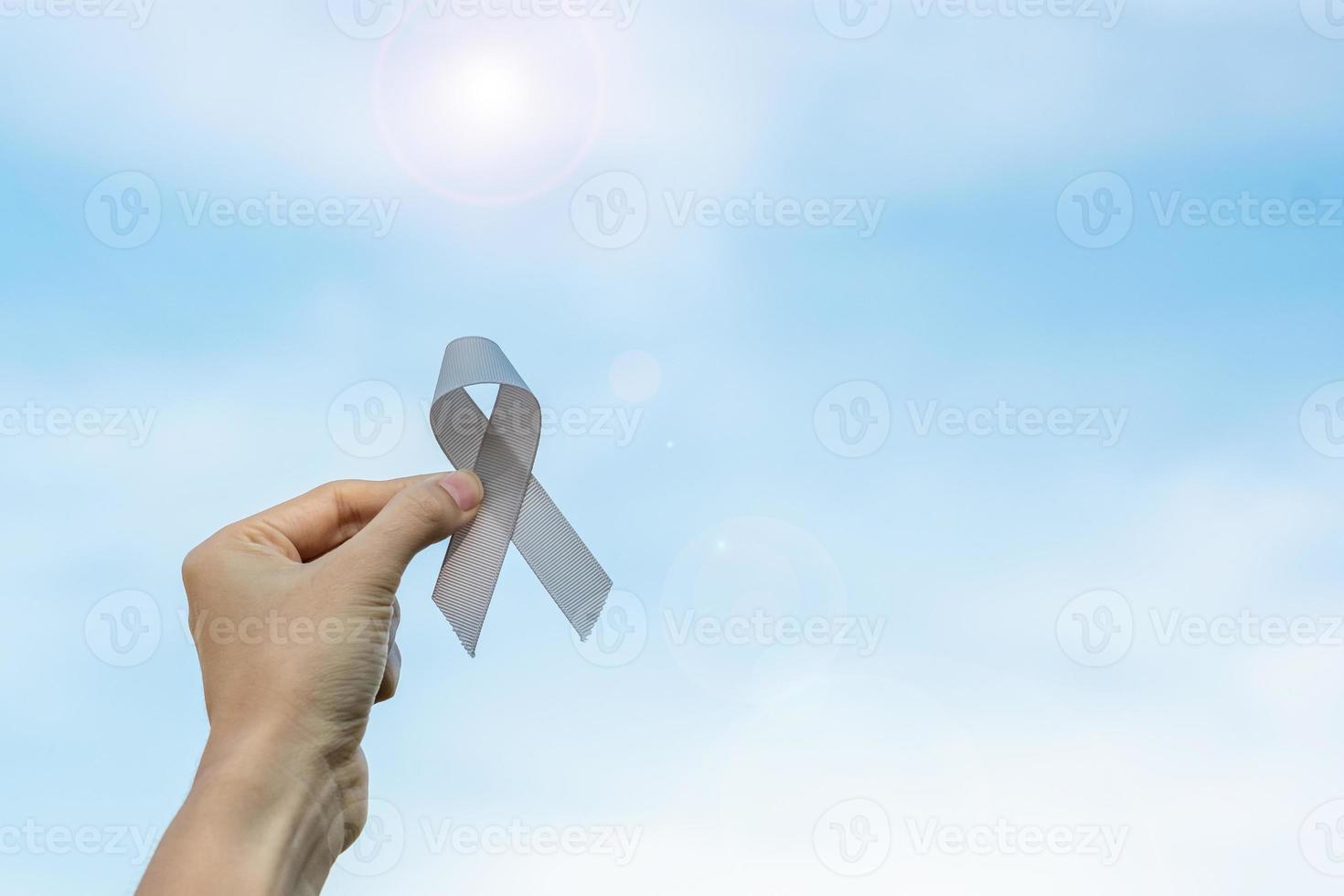 mes de concientización sobre el cáncer cerebral, mano de mujer sosteniendo una cinta de color gris para apoyar a las personas que viven. concepto de salud y día mundial del cáncer foto