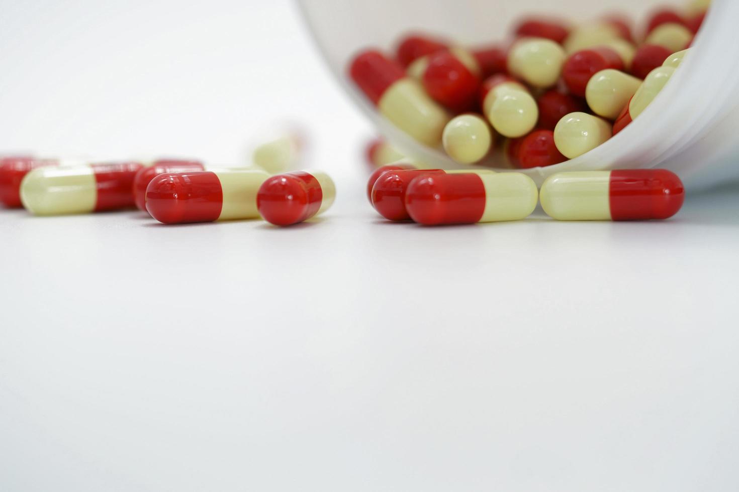 Red and yellow capsules pill in opened white plastic bottle container. Global healthcare concept. Antibiotics drug resistance. Antimicrobial capsule pills. Pharmaceutical industry. Global healthcare. photo