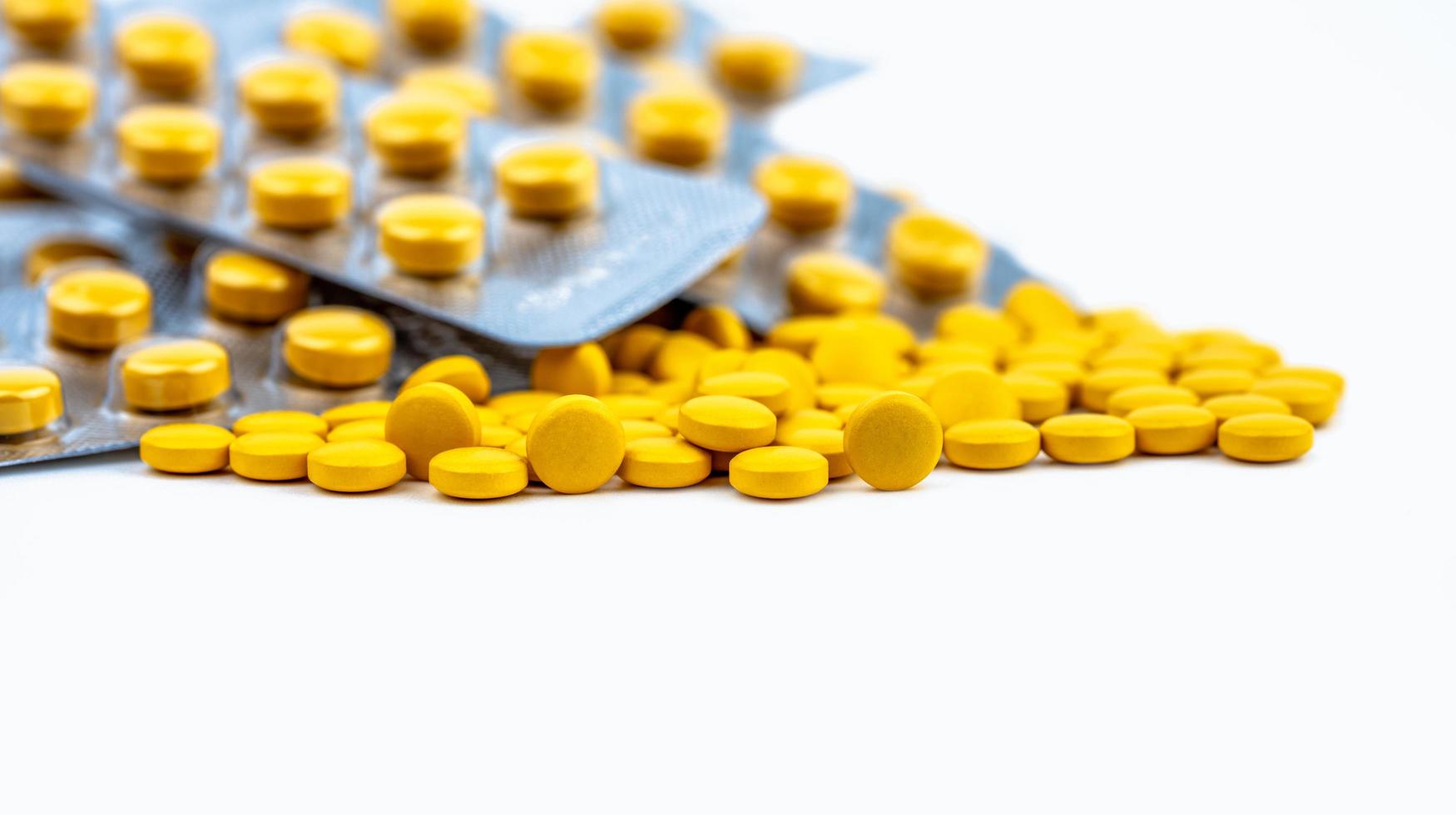 Yellow tablets pills and blister pack. Pharmacy drugstore background. Pharmaceutical industry. Pharmaceutics concept. Selective focus on small yellow tablets pills. Healthcare and medicine concept. photo