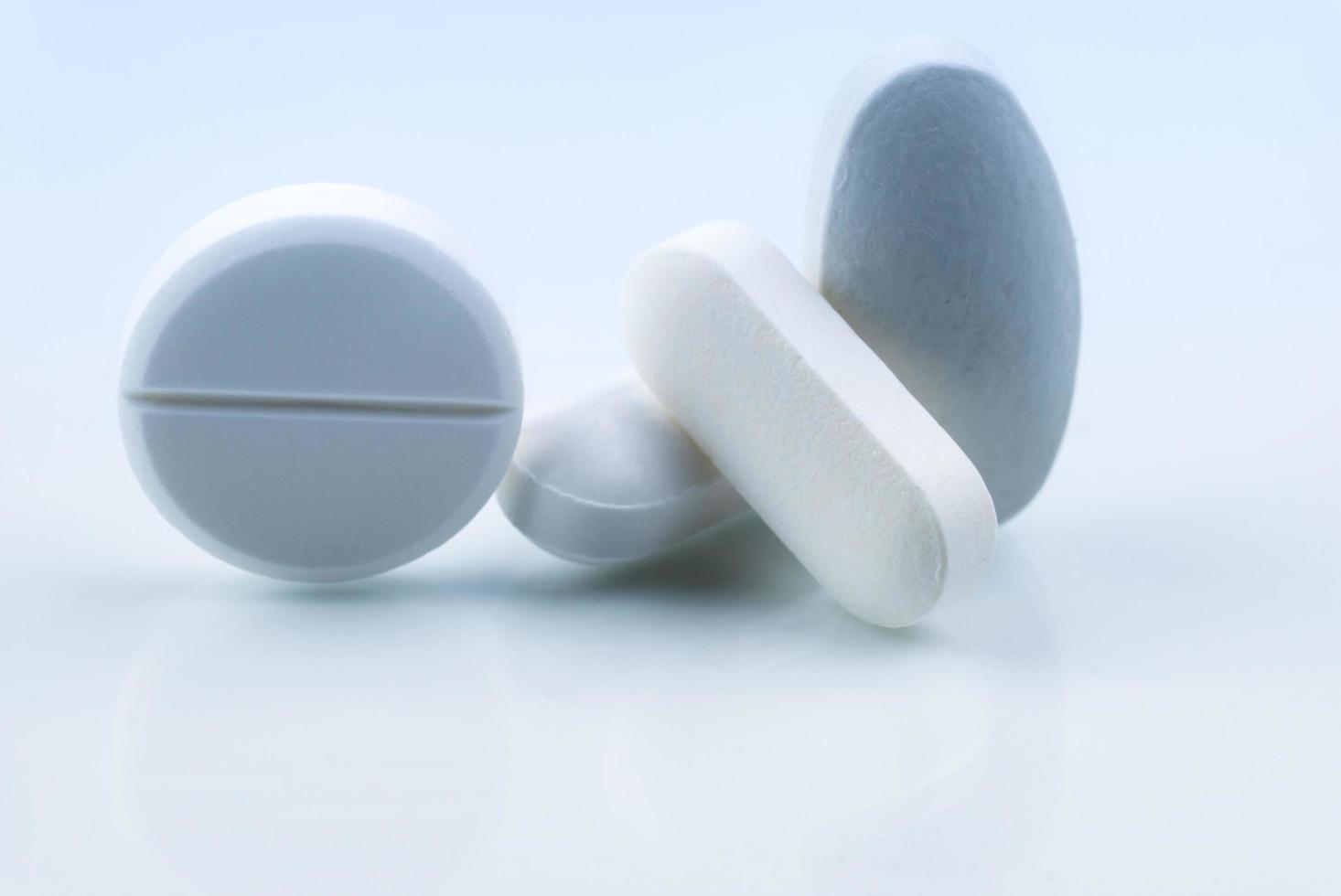 Pile of white round and oblong shape tablet pills isolated on white background. Pharmaceutical industry. Pharmacy or drugstore sign and symbol. Global healthcare concept. Health and pharmacology. photo