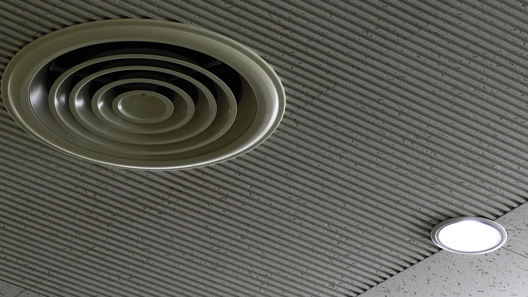 Air duct on ceiling in the mall or hospital. Air conditioner install on gypsum ceiling near ceiling lamp. Building interior concept. Air heading unit on gypsum wall. Cool system in the building. photo