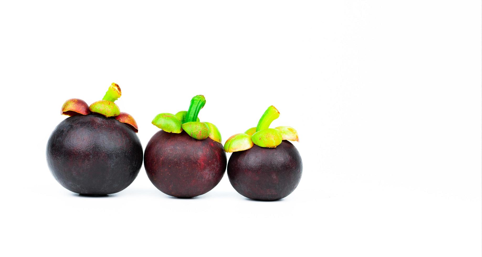Whole mangosteen showing purple skin isolated on white background with space. Tropical fruit from Thailand. The queen of fruits. Asia fresh fruit market concept. Natural source of tannin and xanthones photo