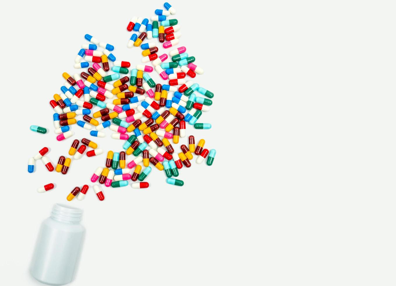 Pouring antibiotics capsule pills into plastic bottle on white background with copy space. Drug storage, antibiotic drug use with reasonable, health policy and health insurance concept. photo