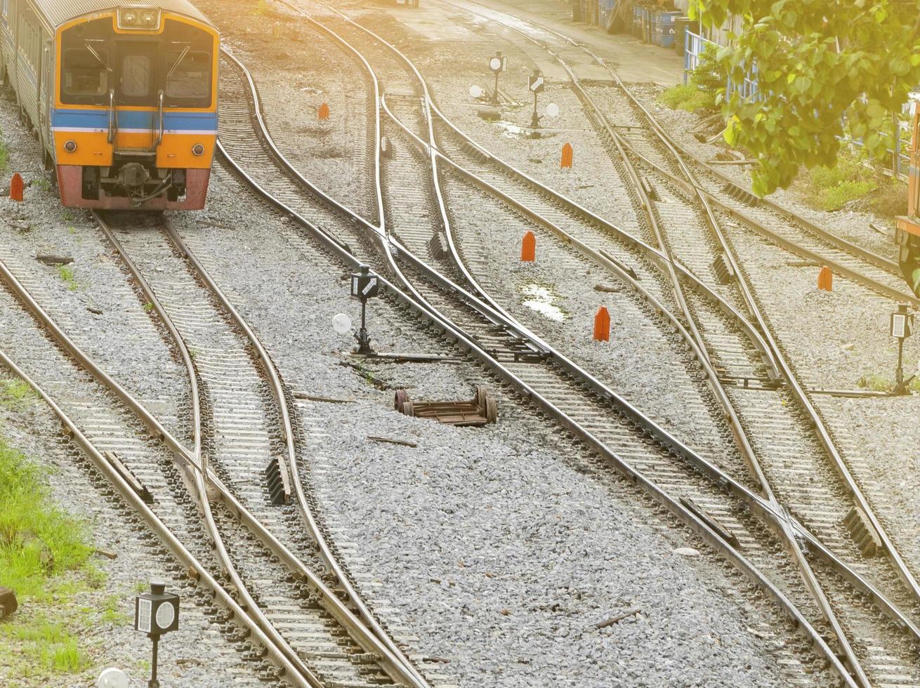 Train track and traffic sign between railway. Journey by train in the morning with warm sunrise light. Local transportation. Travel on summer by train. Junction of railroad track. Nostalgia concept. photo