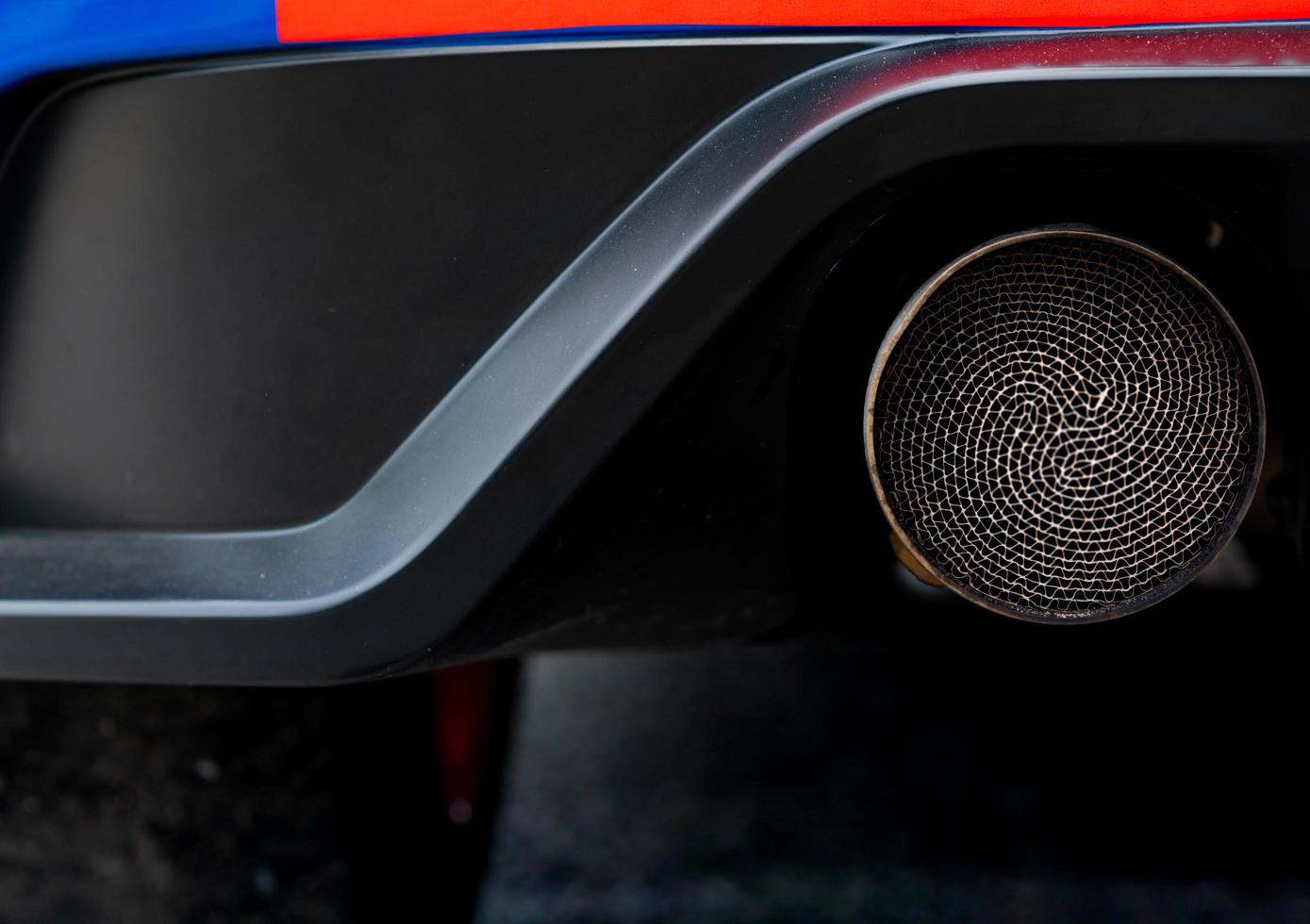 Close up detail exhaust pipe of blue SUV car. Unique pattern of car exhaust pipe. Accessories for sports car. Black soot on old exhaust pipe of gasoline engine car photo