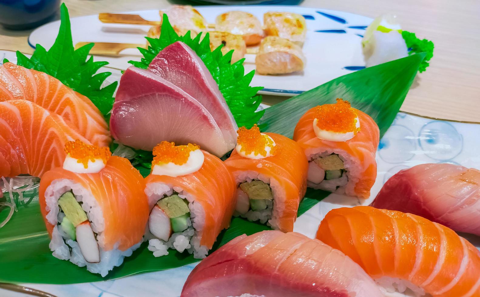 combo de comida japonesa en plato blanco. sushi de salmón, sashimi y nigiri en la mesa del restaurante. rollos de carne de pescado en rodajas y arroz con vinagre de Japón con mariscos y verduras. comida japonesa saludable. foto