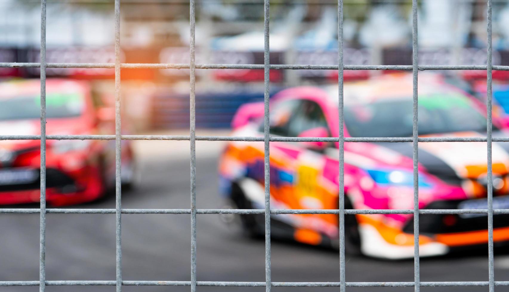 Motorsport car racing on asphalt road. View from the fence mesh netting on blurred car on racetrack background. Super racing car on street circuit. Automotive industry concept. photo