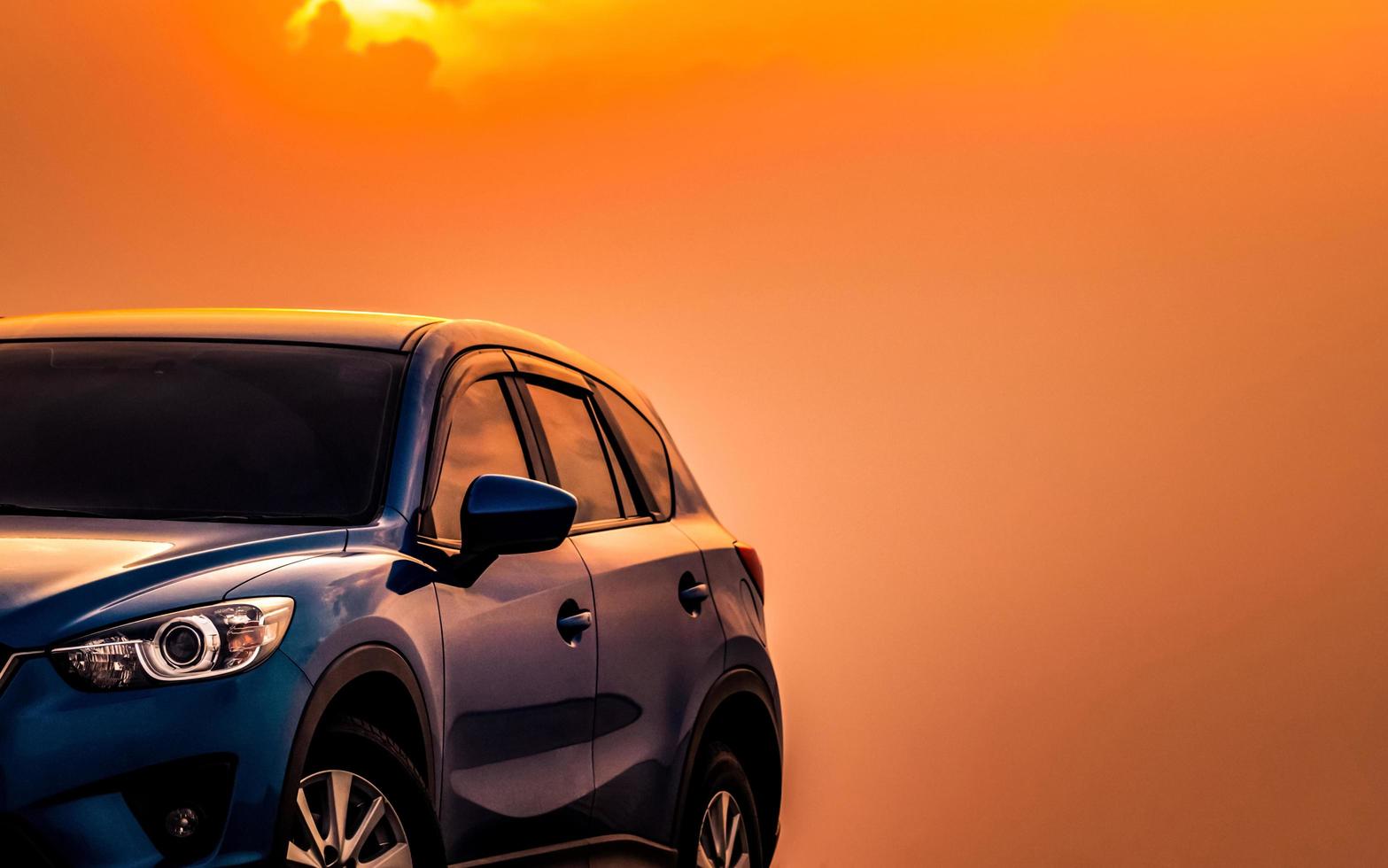Blue compact SUV car with sport and modern design parked on concrete road by the sea at sunset in the evening. Hybrid and electric car technology concept. Car parking space. Automotive industry. photo