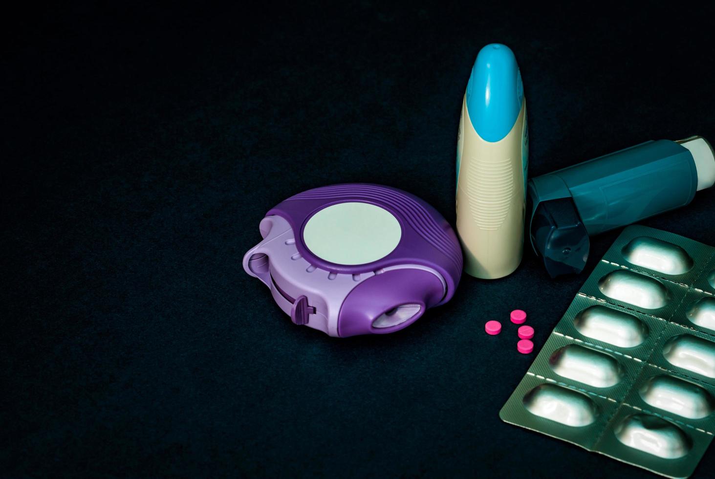Set of asthma inhaler, accuhaler and anti-allergy pills for treatment asthma. Asthma controller, reliever equipment on dark table with copy space. Bronchodilator and steroids drug for severe asthma. photo