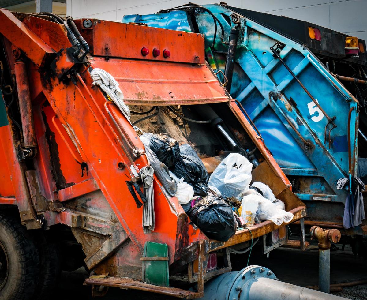 Back of old garbage truck with waste. Urban waste management concept. photo