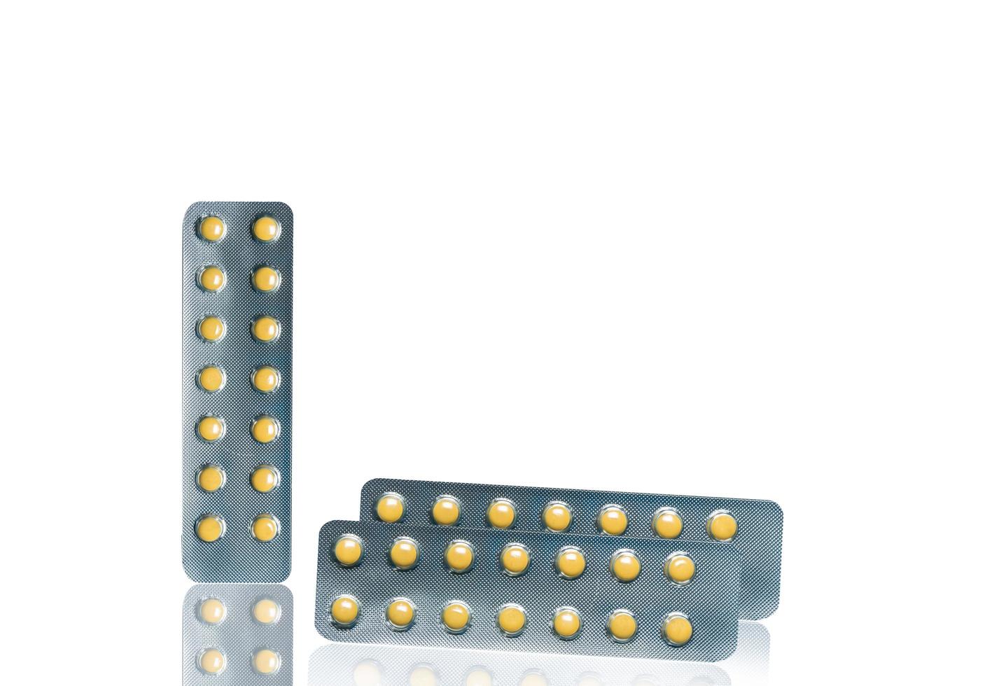 Small round light yellow enteric-coated tablet pills in blister pack isolated on white background with copy space. Medicine for treatment gastric ulcer stomach ulcer or GERD. photo