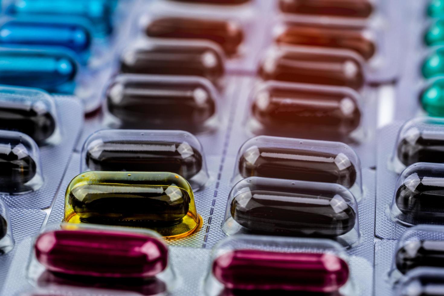 Selective focus expired capsule pill with physical change. Defective and error in pharmaceutical factory concept. Drug production, Vitamins and supplements. Black, red, blue, and green soft gel pills. photo