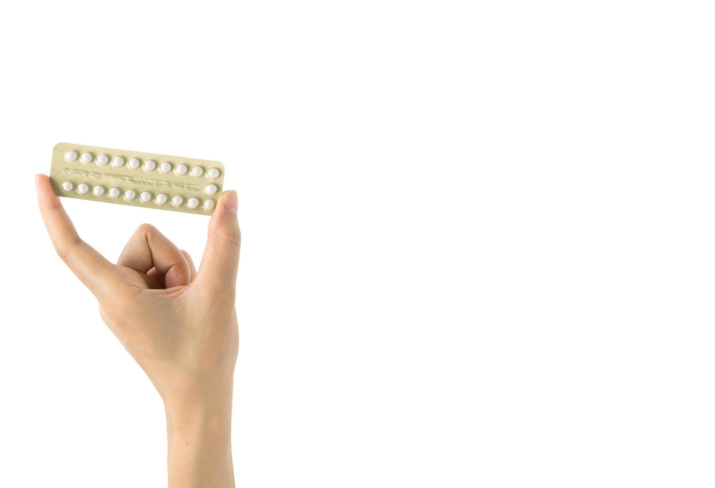 Asian young woman holding pack of contraceptive pills with one hand isolated on white background with copy space and clipping path. Choosing family planning with birth control pill concept photo