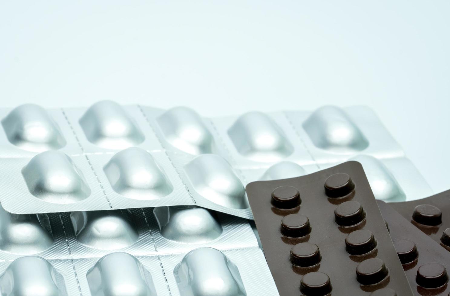 Silver aluminium blister pack and brown blister pack for light resistance packaging to protect drug degradation. Tablet pills packaging isolated on white background photo