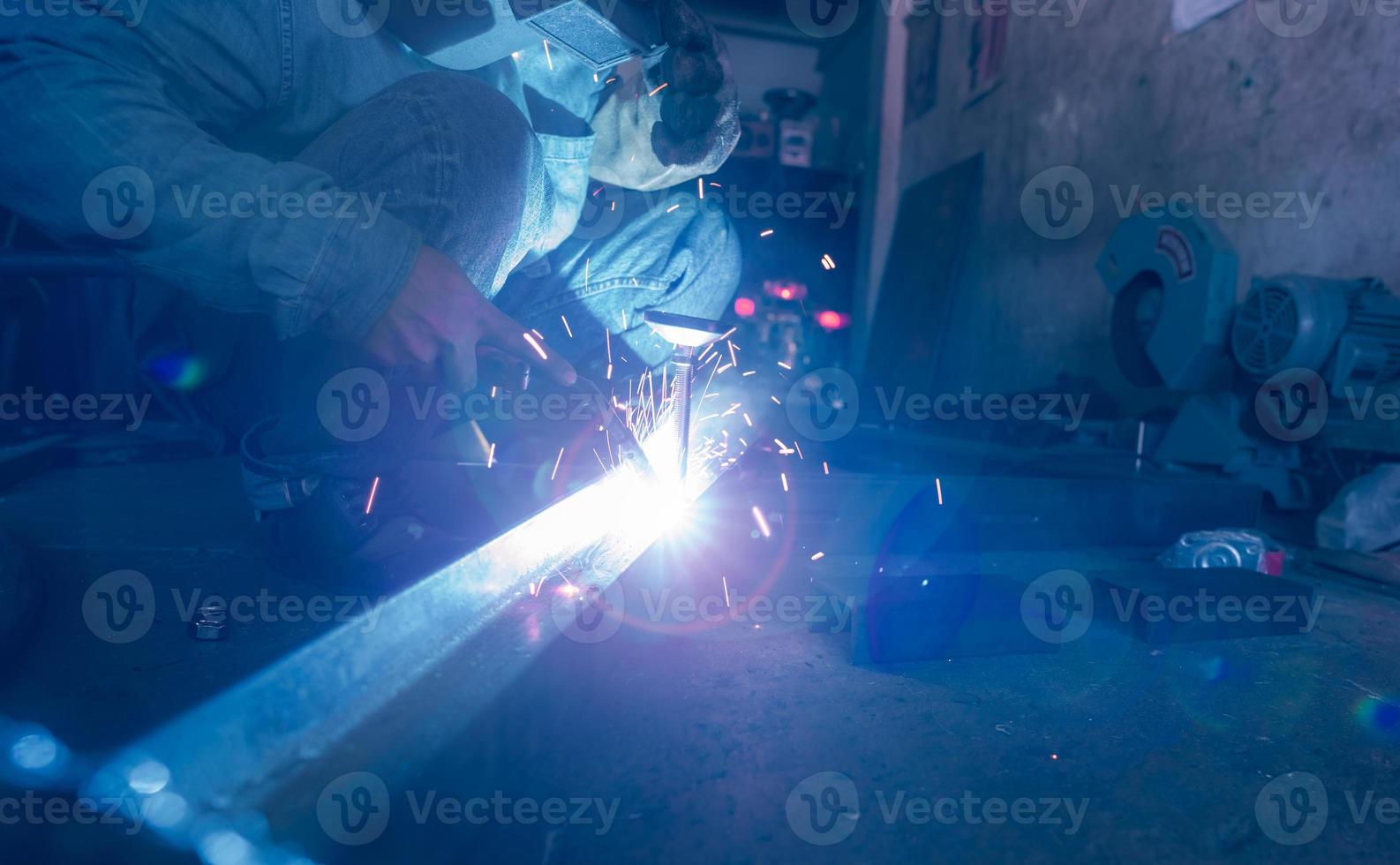 Welder welding metal with argon arc welding machine and has welding sparks. A man wears welding mask and protective gloves. Safety in industrial workplace. Welder working with safety. Steel industry. photo