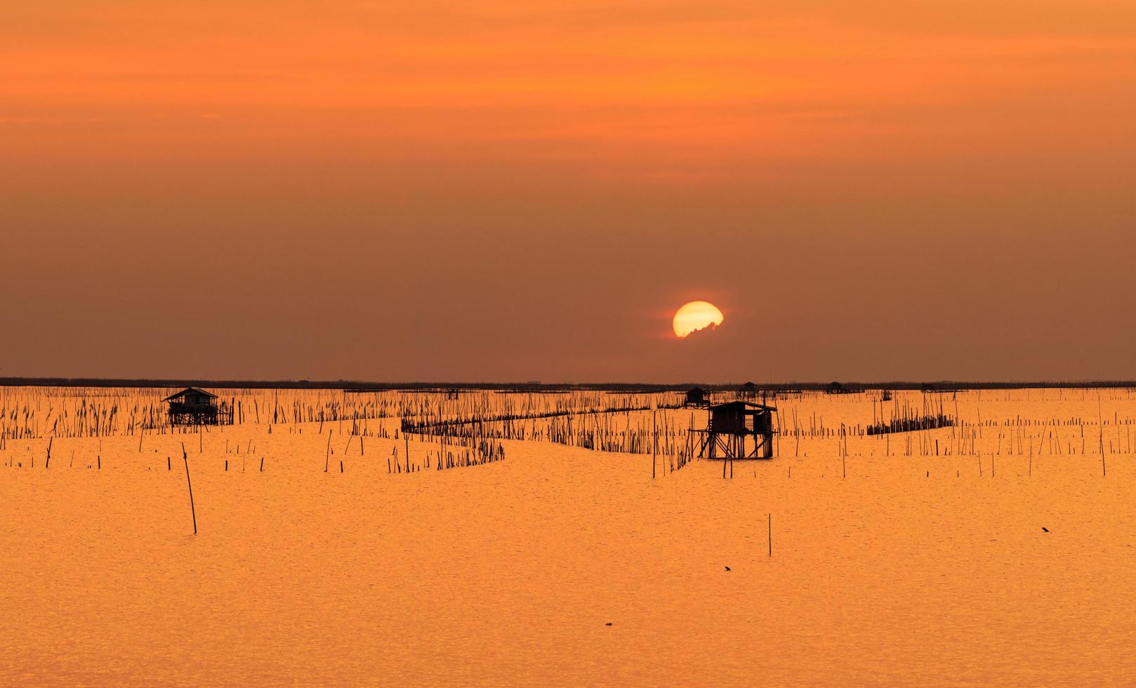 Beautiful sunset sky over the sea in the evening. The sun is obscured by some clouds at sunset. Fisher man hut of coastal fishing in Thailand. Sea at dusk. Silhouette seascape and hut at coastal. photo